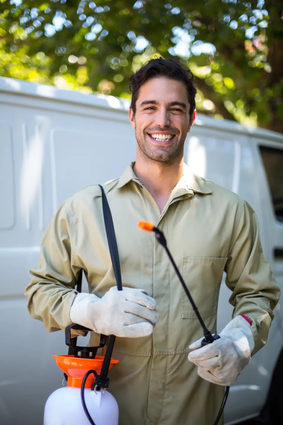 Técnico de control de plagas sonriendo junto a su furgoneta